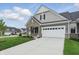 View of the home from the driveway, showcasing the garage, stone facade, and well-maintained landscaping at 16955 Cole Evans Dr, Noblesville, IN 46060