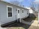 Side view of house showing access door, new siding, and concrete pathway at 2406 E 10Th St, Anderson, IN 46012
