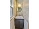 Compact bathroom with vanity, grey cabinet, tiled walls, and a charming round mirror above the sink at 3470 N Kenwood Ave, Indianapolis, IN 46208