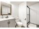 Clean bathroom with a walk-in shower, modern vanity and a wicker-framed mirror at 3652 N Delaware St, Indianapolis, IN 46205