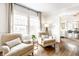 Bright living room featuring two comfortable armchairs, hardwood floors, and an open doorway to the dining area at 3652 N Delaware St, Indianapolis, IN 46205