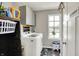 Well-organized laundry area with gray cabinets, washer, dryer, and natural light from the window at 4345 Maize Ln, Whitestown, IN 46075