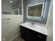 Bathroom featuring marble tiled shower, dark vanity with quartz countertops, and LED mirror at 5105 Manning Rd, Indianapolis, IN 46228