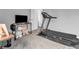 Neutral colored bedroom with a modern treadmill, side table, and television setup at 5524 Cherry Blossom Ct, Indianapolis, IN 46237