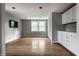 Open living room with hardwood floors, a large window, and a wet bar area with white cabinets at 650 Forest Blvd, Indianapolis, IN 46240