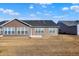Backyard view of a single Gathering home with a black roof and brown siding on a partially-grassed lot at 7111 Lillian Pl, Cumberland, IN 46229
