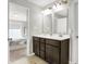 Bathroom with double sinks, dark cabinets, large mirrors, and neutral tile flooring at 7111 Lillian Pl, Cumberland, IN 46229