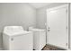 Bright laundry room features a Whirlpool washer and dryer, with a white paneled door and wood-look floors at 7111 Lillian Pl, Cumberland, IN 46229