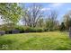 A large grass backyard featuring mature trees, garden, storage shed, and a wooden fence adding privacy to the property at 7263 Hidden Valley Dr, Plainfield, IN 46168