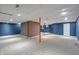 Large unfinished basement featuring blue walls, brick accents, neutral carpeting, and ample space for customization at 8259 Plumwood Ln, Indianapolis, IN 46256
