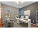 Modern office with a white desk, accent wall, shelves, and two windows offering natural light at 8259 Plumwood Ln, Indianapolis, IN 46256
