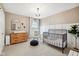 Charming bedroom featuring a crib, dresser, rocker, and natural light from the window at 8834 Pin Oak Dr, Zionsville, IN 46077