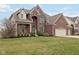 Charming two-story brick home with a well-manicured lawn, rocking chair front porch, and attached garage at 8834 Pin Oak Dr, Zionsville, IN 46077