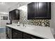 Well-lit kitchen with dark cabinets, mosaic backsplash, and a sleek stainless steel dishwasher at 9242 Golden Leaf Way, Indianapolis, IN 46260
