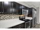 Contemporary kitchen with stainless steel appliances, dark cabinets, and a stylish backsplash at 9242 Golden Leaf Way, Indianapolis, IN 46260