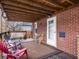 Covered back porch featuring a cozy seating area, brick siding, and natural light at 1237 E Pleasant Run Pkwy S Dr, Indianapolis, IN 46203