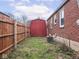 Fenced backyard with a storage shed, grassy area, and access to the brick house at 1237 E Pleasant Run Pkwy S Dr, Indianapolis, IN 46203