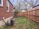Fenced backyard with grass, air conditioning unit, and brick siding on house at 1237 E Pleasant Run Pkwy S Dr, Indianapolis, IN 46203