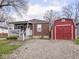 A brick home featuring a front porch and a large, red barn style outbuilding with double doors at 1237 E Pleasant Run Pkwy S Dr, Indianapolis, IN 46203