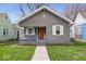 Charming bungalow featuring a textured gray exterior, orange front door, and a cozy front porch at 1310 N Chester Ave, Indianapolis, IN 46201
