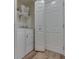 A functional laundry room with a washer, dryer, storage shelves, and access to an exterior door at 1739 Wellesley Commons # 48A, Indianapolis, IN 46219