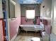 Bathroom with pink tiling, white fixtures, and damage to the walls and ceiling at 2148 Singleton St, Indianapolis, IN 46203