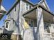 Exterior shot of a house with light gray wood siding and a covered porch with a yellow front door at 2148 Singleton St, Indianapolis, IN 46203