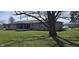 Large backyard with a spacious lawn, shaded by a mature tree and a screened-in patio at 3002 W 53Rd St, Anderson, IN 46011