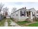 Tan house with vinyl siding, side driveway, and a detached garage on a cloudy day at 3420 N Chester Ave, Indianapolis, IN 46218