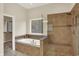 Luxurious bathroom featuring a soaking tub, tiled shower with a bench, and stone pebble flooring at 3715 Kendall Wood Dr, Carmel, IN 46032