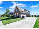 This two-story brick home has a three-car garage with a long concrete driveway, side-facing exterior, and manicured lawn at 3715 Kendall Wood Dr, Carmel, IN 46032