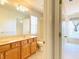Bathroom with double vanity, oak cabinets, and a view of a bright bedroom through a doorway at 3926 Castle Rock Dr, Zionsville, IN 46077