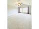 Spacious carpeted bedroom with a ceiling fan, three windows with lilac-colored curtains, and gray walls at 3926 Castle Rock Dr, Zionsville, IN 46077