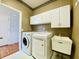 Laundry room with white cabinets, wallpaper, washer, dryer, and sink at 3926 Castle Rock Dr, Zionsville, IN 46077