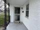 A bright, covered front porch features white painted brick and trim, and dark accents at 4121 Fletcher Ave, Indianapolis, IN 46203