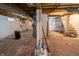 Unfinished basement with painted walls and floor, staircase, water heater, and supporting columns at 4711 East 21St St, Indianapolis, IN 46218