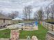 Backyard pool with mature trees, lounge furniture, and a white dining set on the back patio at 4808 N Camelot Dr, Muncie, IN 47304