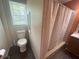 Bathroom featuring a toilet, shower curtain, dark wood floors, and orange walls with exposed drywall at 554 N Tacoma Ave, Indianapolis, IN 46201