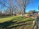 A large backyard featuring lush greenery, a trampoline, and a wooden deck for relaxation at 7211 Kensington Ct, Avon, IN 46123