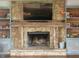 Cozy living room featuring a stone fireplace with a TV, custom built-ins, and wood floors at 7211 Kensington Ct, Avon, IN 46123