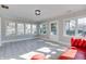 Bright sun room with white trim, tiled floor, many windows, and a red couch at 7525 N Meridian St, Indianapolis, IN 46260