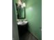 This half bath has a green wall, dark vanity and a small mirror with an ornate frame at 9235 Thrushwood Ln, Indianapolis, IN 46250