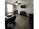 Bright and cozy living room featuring wood-look floors, large window, and dark-leather sofas at 9235 Thrushwood Ln, Indianapolis, IN 46250