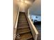 A staircase with hardwood steps, leading to the upper level, features freshly painted white risers at 9235 Thrushwood Ln, Indianapolis, IN 46250