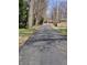 Long, cracked asphalt driveway leading to the main street, lined with tall trees at 930 Charlene Ln, Anderson, IN 46011