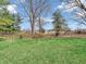 Spacious backyard with lush lawn, mature trees and a metal fence at 9406 Northeastern Ave, Indianapolis, IN 46239