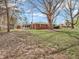 Red brick home featuring a screened-in porch and a spacious backyard with mature trees at 9406 Northeastern Ave, Indianapolis, IN 46239