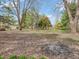 Large backyard with mature trees, an open lawn, and a fire pit at 9406 Northeastern Ave, Indianapolis, IN 46239