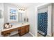 Bathroom with wood vanity, and framed mirror illuminated by a three-light fixture, and a blue patterned shower curtain at 1043 Palomar Dr, Westfield, IN 46074