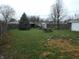 Large backyard featuring lush lawn, mature trees, picnic table, sheds, and a well-kept lawn at 1106 N Hartman Dr, Indianapolis, IN 46219